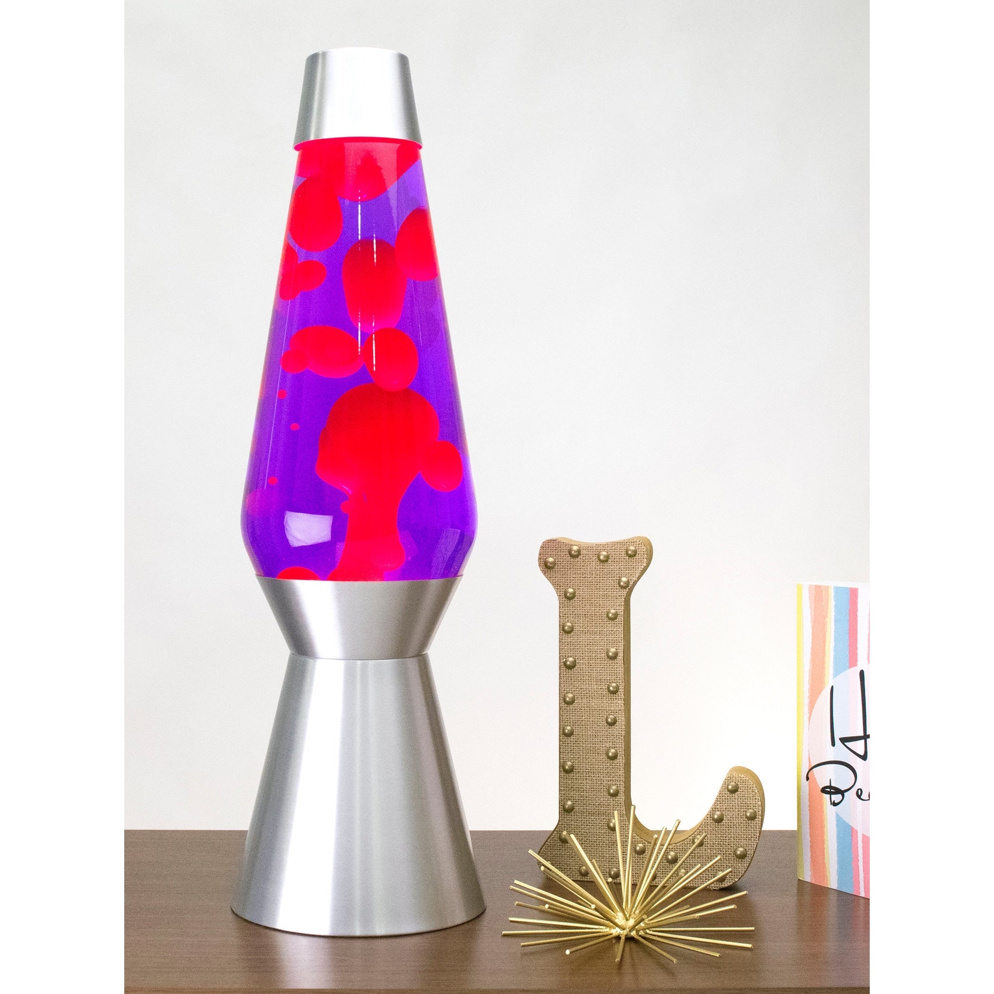 27” LAVA® Lamp Grande – Pink/Purple/Silver on a table with knick knacks